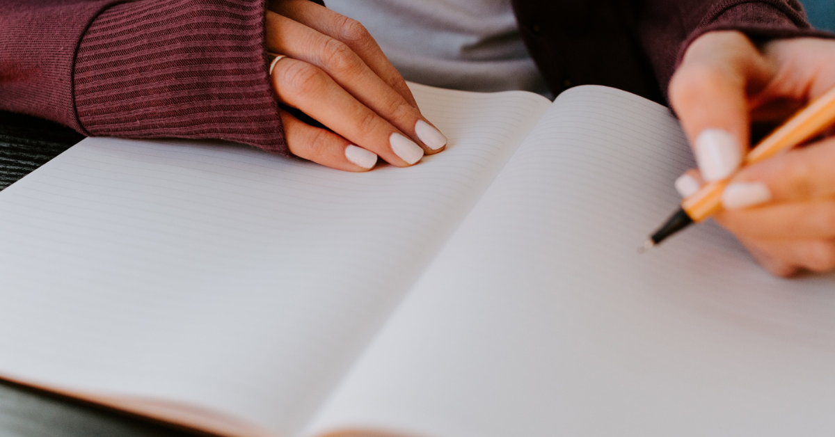 hands, hand holding a pen, hands on a journal, female hands, writing, goal setting, health journal