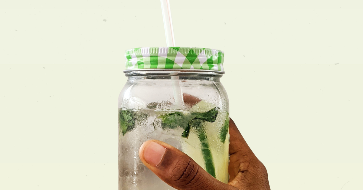 person holding clear glass jar of water with green and white lid