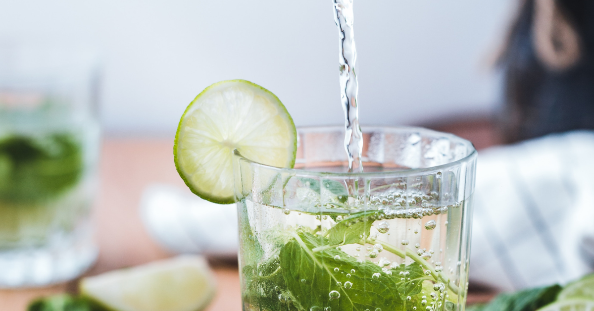 water pouring into a glass with mint and lime