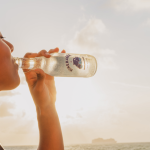 woman drinking mineral water with the ocean in the background