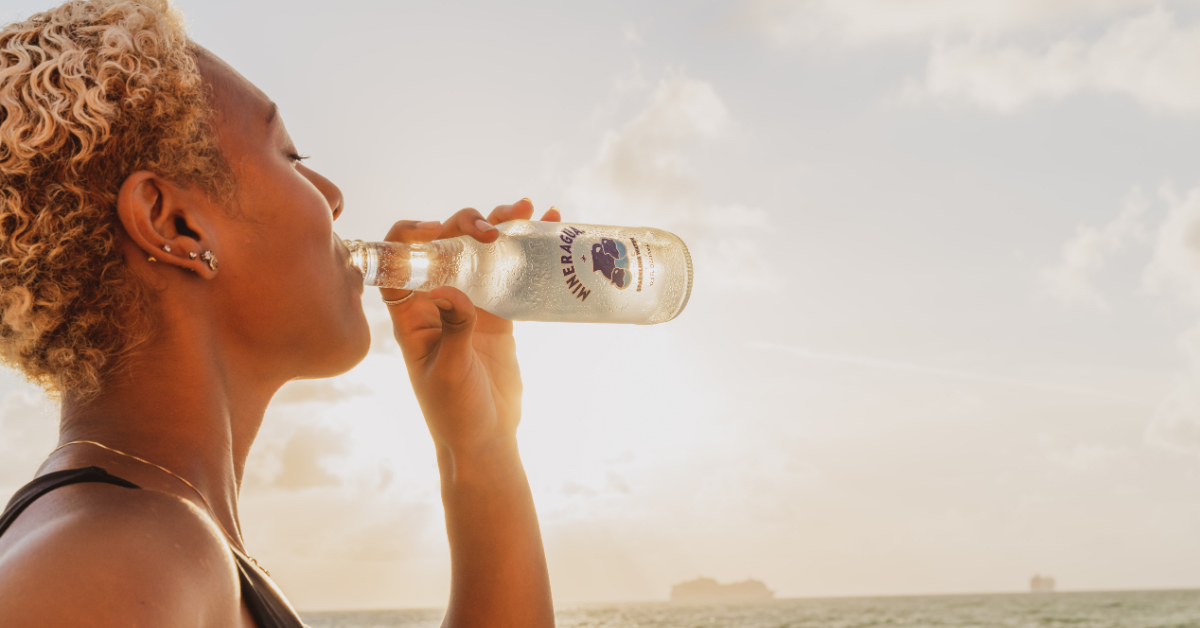 woman drinking mineral water with the ocean in the background
