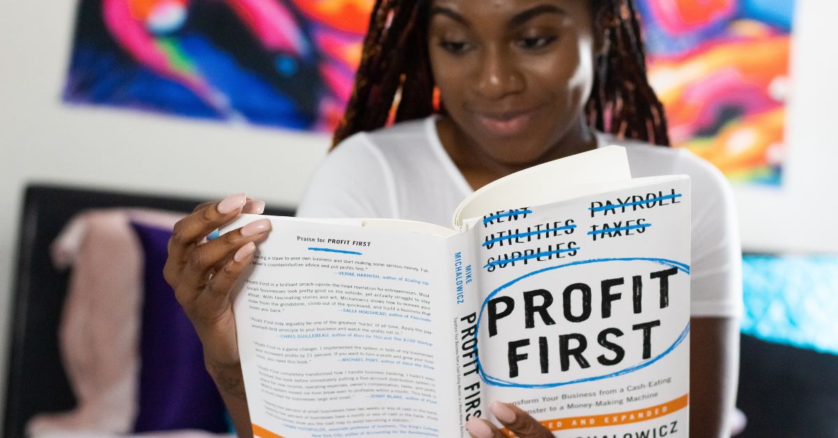 woman reading a book titled "profit first"