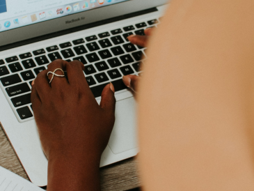 a person in a hat working on a macbook air