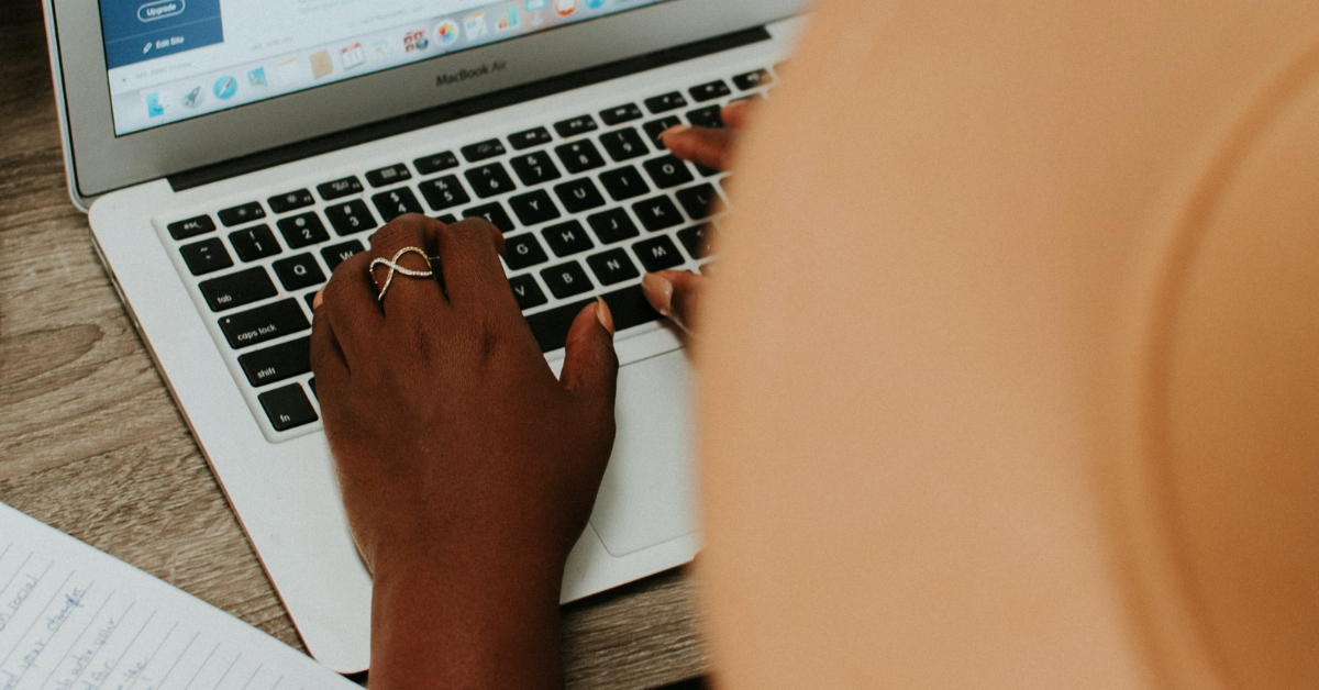 a person in a hat working on a macbook air