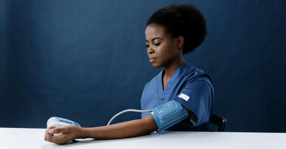 a healthcare worker measuring her own blood pressure using a sphygmomanometer