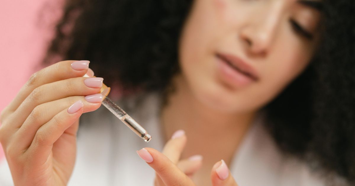 close up of woman putting serum on her finger with the use of a pipette